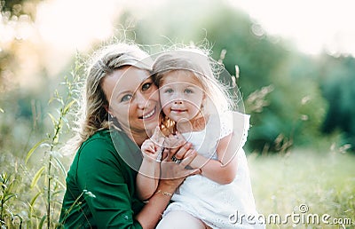 A portrait of young mother in nature with small daughter in summer. Stock Photo