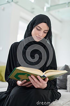 Portrait of young muslim woman reading Quran in modern home Stock Photo