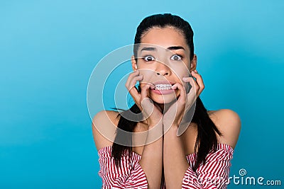 Portrait of young nervous anxious funny chinese girl bite nails scared stressed horrified watching film isolated on blue Stock Photo