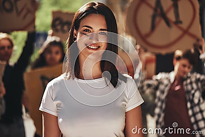 Portrait of young positive female activist with word freedom written on her face looking at camera and smiling while Stock Photo