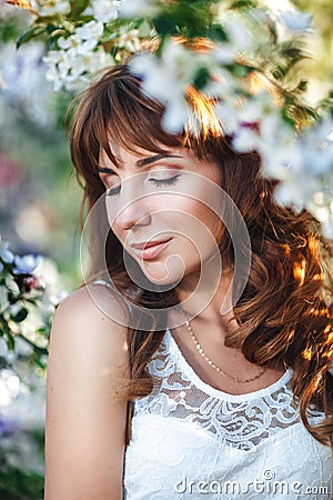 Portrait of a young pretty red-haired woman with closed eyes in a flowery garden, close-up Stock Photo