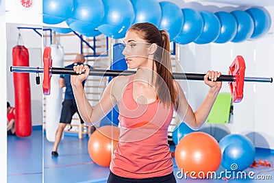 Portrait of a young pretty woman holding crossfit barbell and doing fitness indor. Crossfit hall. Gym shot. Stock Photo