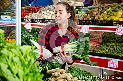 Portrait of a young saleswoman laying out bundles of chinese cabbage on the counter Stock Photo