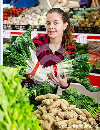 Portrait of a young saleswoman laying out bundles of chinese cabbage on the counter Stock Photo