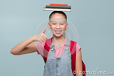 Portrait of a young schoolgirl with books. Thumb up Stock Photo