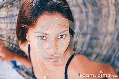 Portrait of young beautiful girl sitting on rattan hammock, blurry background Stock Photo