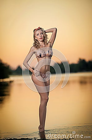 Portrait of young blonde girl in bikini posing provocatively at the beach in sunset. Sensual attractive woman Stock Photo