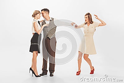 Portrait of young shocked woman catching her man flirting and dancing with another girl. Unfaithfulness in relationship Stock Photo