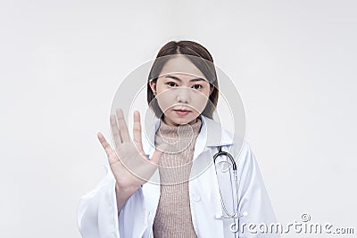 Portrait of a young and skilled doctor, medical student, intern posing with palms faced on the camera, telling someone to stop. Stock Photo