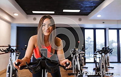 Portrait of young slim woman in sportwear workout on exercise bike in gym. Sport and wellness lifestyle concept Stock Photo