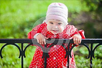 Portrait of a young smiling girl in a red coat with polka dots Stock Photo