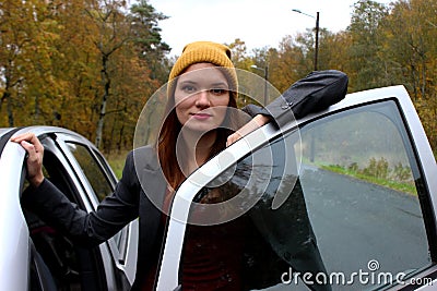 Getting ready. Portrait of young smiling lady standing near car and opening door. Stock Photo