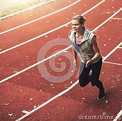 Portrait of young sportswoman running fast on track field Stock Photo