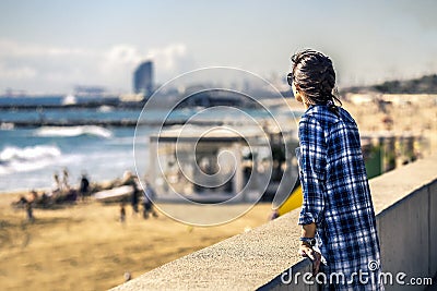 Portrait of young and stylish woman standing on the sea-front next to the sandy beach. Editorial Stock Photo