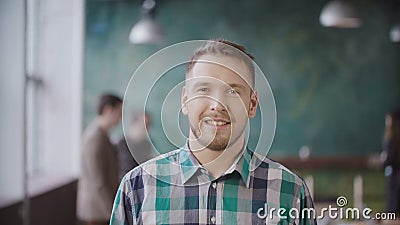 Portrait of young successful businessman at busy office. Handsome male employee looking at camera and smiling. Stock Photo