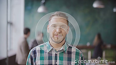 Portrait of young successful businessman at busy office. Handsome male employee looking at camera and smiling. Stock Photo