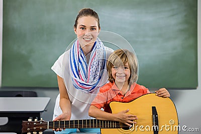 Portrait of young teacher assisting boy to play guitar Stock Photo