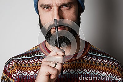 Portrait of Young thoughtful bearded man in blue beanie thinking about test over empty background. Stock Photo