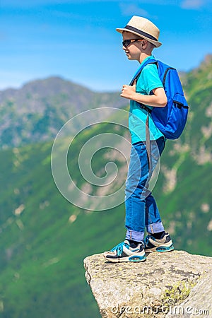 portrait of a young traveler with a backpack high in the mountains on a rock Stock Photo