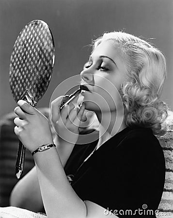 Portrait of a young woman applying a lipstick on her lips Stock Photo