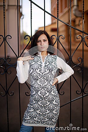 Portrait of a young woman with black hair standing near the metall fence. Young woman modern portrait Stock Photo