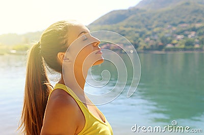 Portrait of a young woman breathe deeply outdoors on lake in a sportswear, head up, her eyes closed. Copy space Stock Photo