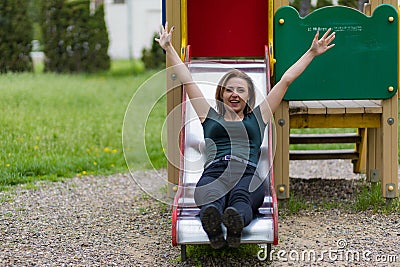 Portrait of a young woman on a childrens slide with copy space. Freedom and happiness concept Stock Photo