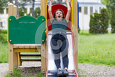 Portrait of a young woman on a childrens slide with copy space. Freedom and happiness concept Stock Photo