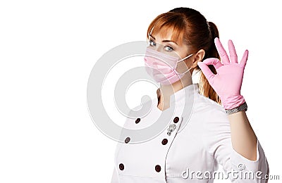 Portrait of young woman doctor or nurse in white medical uniform, gloves and protective mask gesturing OK sign Stock Photo