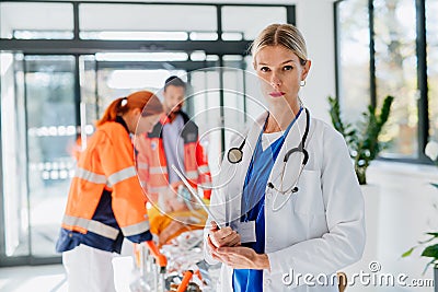 Portrait of young woman doctor with rescuers in background. Stock Photo