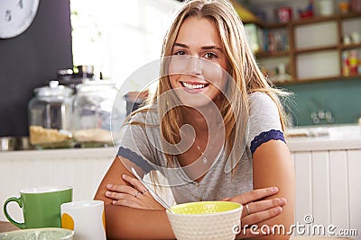 Portrait Of Young Woman Eating Breakfast In Kitchen Stock Photo