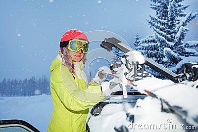 Portrait of young woman fastening skis on car roof Stock Photo