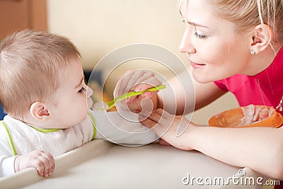 Portrait of young woman feeding her baby Stock Photo