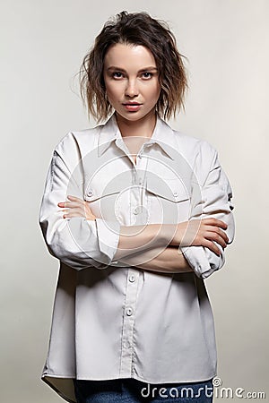 Portrait of young woman on gray background. Female posing in jeans, and milky white corduroy shirt Stock Photo