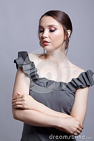 Portrait of young woman in gray dress on grÐµy background Stock Photo