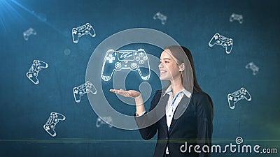 Portrait of young woman holding gamer`s joystick on the open hand palm, over drawn studio background. Business concept. Stock Photo