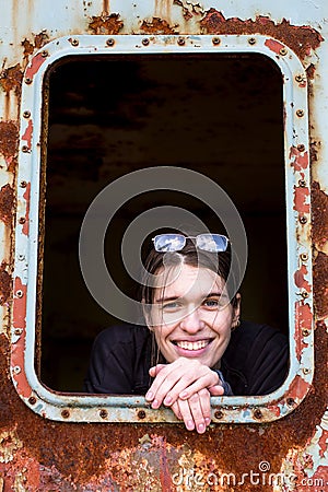 Young woman looking out the window of a rusty wagon. Stock Photo