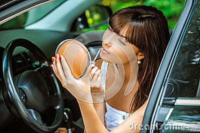 Portrait of young woman making herself up in car Stock Photo