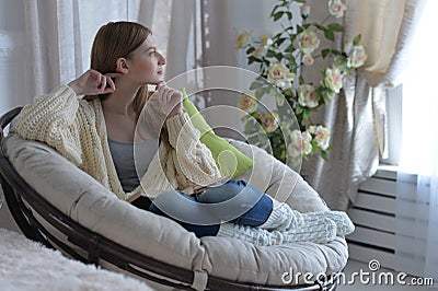 Portrait of young woman in pajamas on bed with fluffy plaid Stock Photo