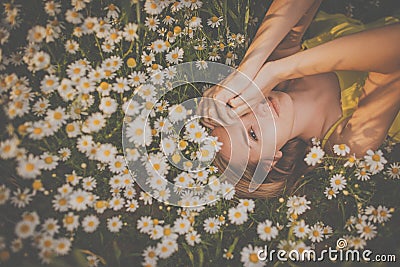 Portrait of young woman with radiant clean skin lying down amid flowers on a lovely meadow Stock Photo