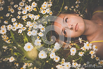 Portrait of young woman with radiant clean skin lying down amid flowers on a lovely meadow Stock Photo