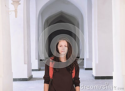 Portrait of a young woman standing in a corridor of white arabian arches in Kalyan Mosque, Bukhara, Uzbekistan Stock Photo