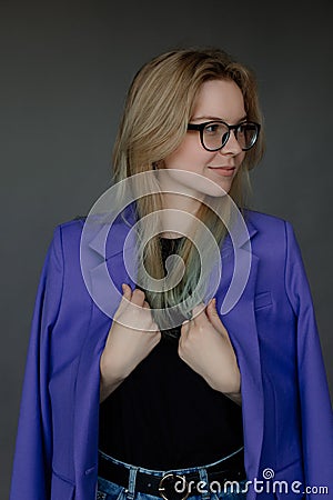 Portrait of young woman in stylish blue female blazer and glasses looking away, gray background, free copy space. New Stock Photo