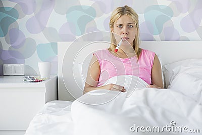 Portrait of young woman taking temperature with thermometer Stock Photo