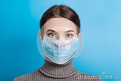 Portrait of young woman wearing medical mask with MERS word at blue background. Protect your health. concept Stock Photo