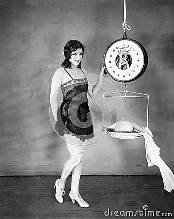 Portrait of a young woman weighing her clothes on a weighing scale Stock Photo