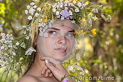 Portrait of a young woman in a wreath of flowers closeup with a dreamy expression on her face Stock Photo