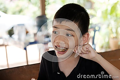 Portraits Cute Asian Thai Boy eats grilled pork with deliciousness exciting action Stock Photo