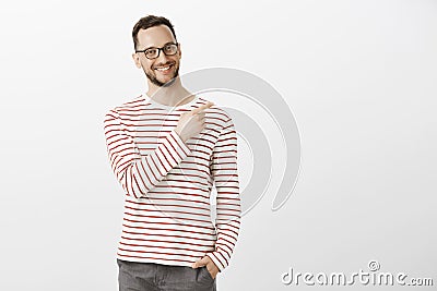 Portrat of proud confident aduly guy in glasses, holding hand in pocket and pointing at upper right corner with broad Stock Photo