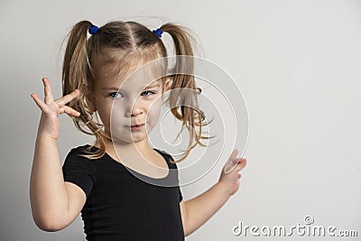 portret emotional 4 year old girl with two ponytails. one hand shows on copy space to the right of itself, Stock Photo